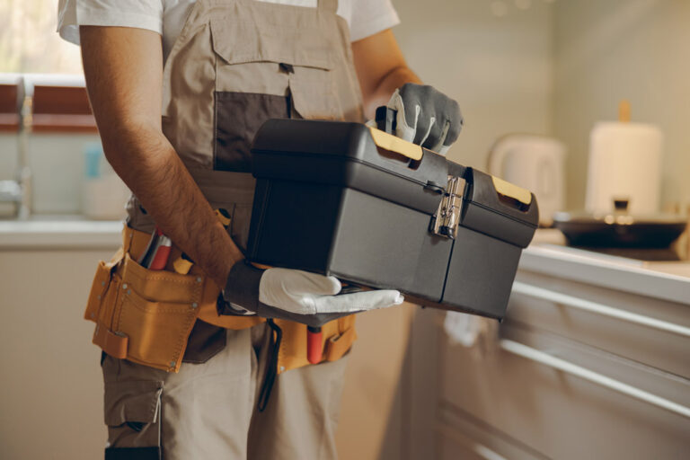 close up professional handyman standing home kitchen holding his tool bag 2 768x512