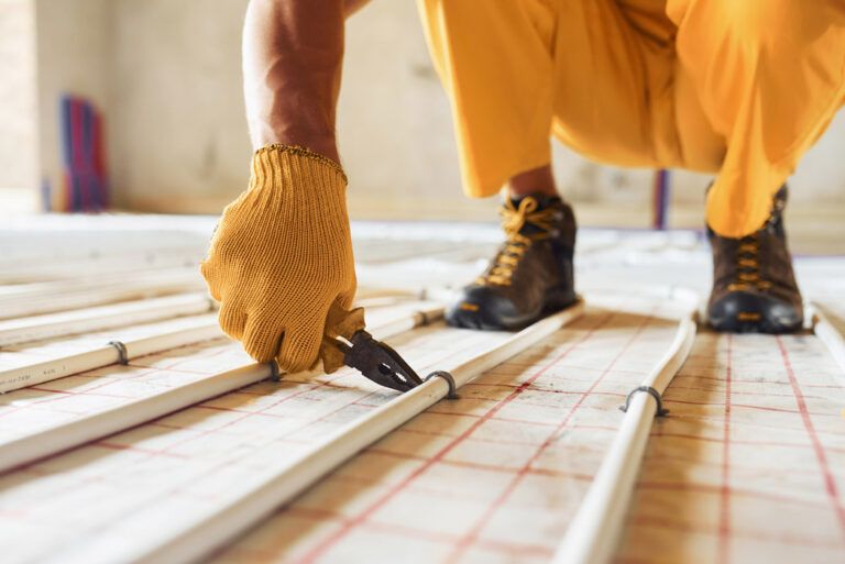close up view worker yellow colored uniform installing underfloor heating system 1 768x513