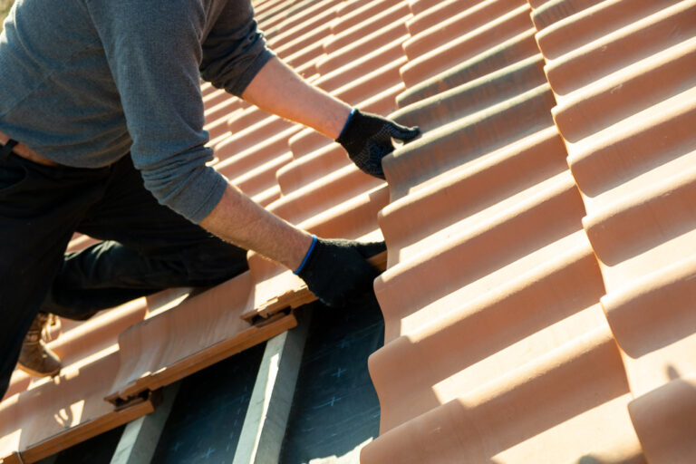 closeup worker hands installing yellow ceramic roofing tiles mounted wooden boards covering residential building roof construction 2 768x512