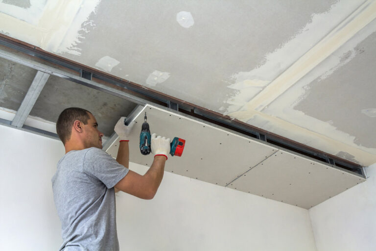 construction worker assemble suspended ceiling with drywall with screwdriver 1 768x512
