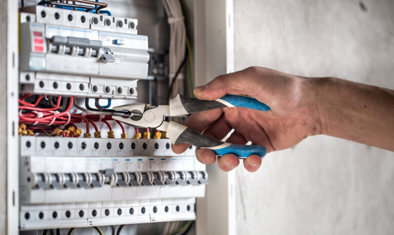 electrical technician working switchboard with fuses 768x459