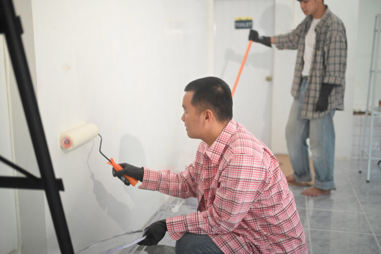 two young asian men painting walls with roller brush renovation 768x512